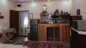 Une cuisine compacte équipée d’une cuisinière intégrée, d’un réfrigérateur et d’un four à micro-ondes. On y trouve un meuble en bois et un crédence décorée.