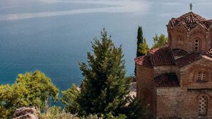 Une église coiffée d’un toit de tuiles rouges, qui surplombe une vaste étendue d’eau.