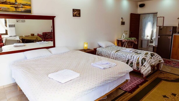 Une chambre d’hôtel avec un grand lit, un lit plus petit, un bureau et une armoire.