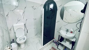 Une salle de bain équipée de toilettes, d’un bidet et d’une douche.