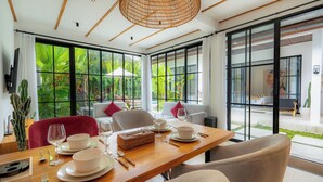 A dining area with a wooden table set for four, surrounded by white chairs. - Milla Villa by Betterplace (Ubud)