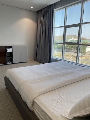 A hotel room with a large bed, a wardrobe, a desk, and a window with a view of the landscape. - Qimam Park 5 Abha (Abha)