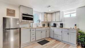 Une cuisine moderne dotée d’appareils électroménagers en acier inoxydable, de meubles de couleur claire et d’un tapis noir.