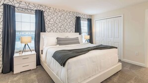 A bedroom with a bed, bedside tables, a lamp, a patterned wall, and a door. - Beautiful Storey Lake Retreat, Minutes from Disney (Kissimmee)