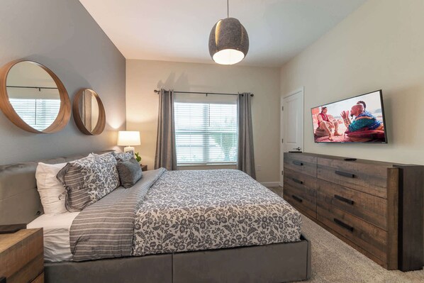 A bedroom with a bed, bedside tables, a dresser, a TV, and a window with curtains. - Beautiful Storey Lake Retreat, Minutes from Disney (Kissimmee)