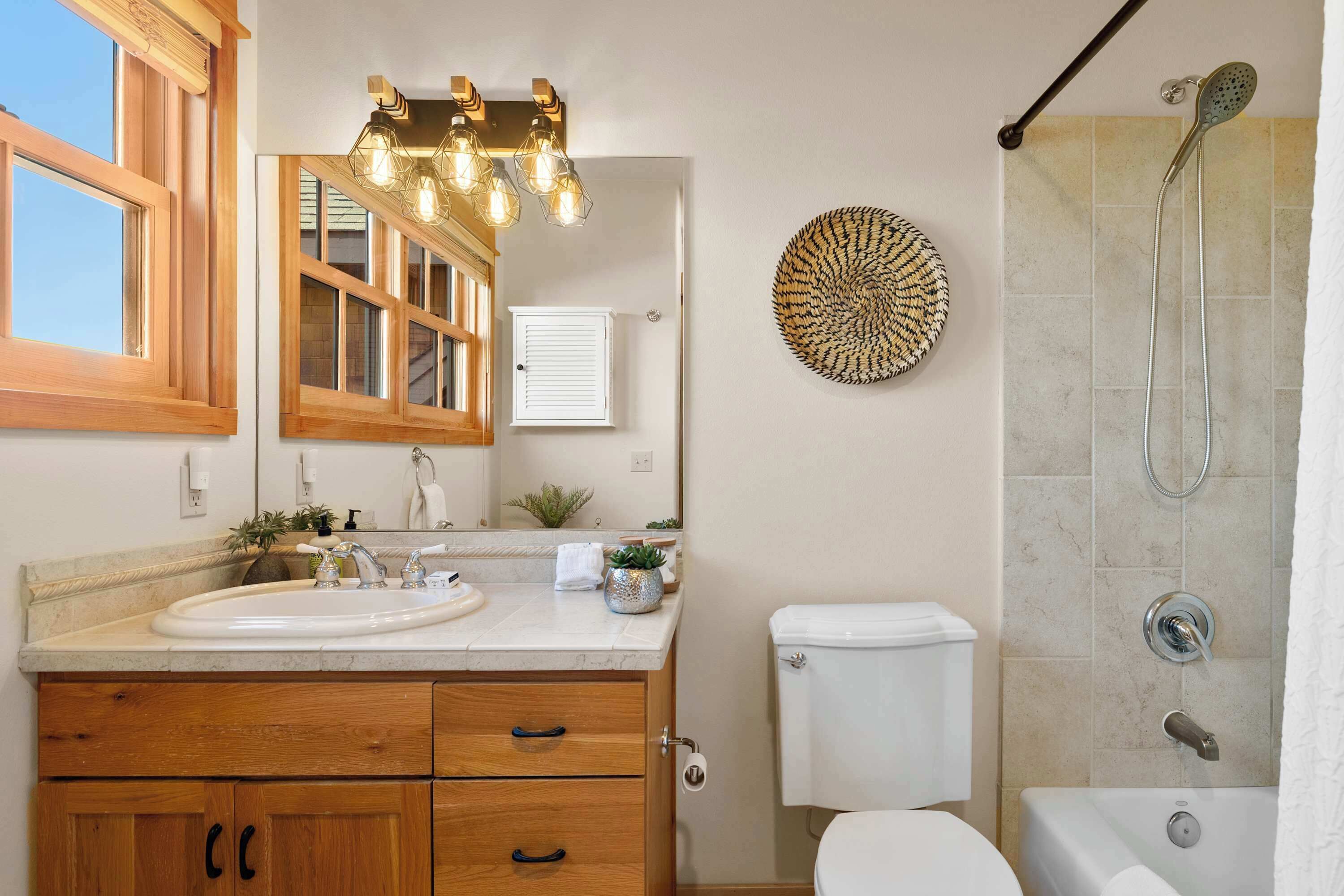 A bathroom with a wooden vanity, a white sink, a mirror, a toilet, and a shower with a glass door.