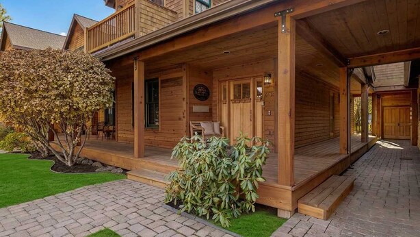 Ett trähus med en veranda, en liten trädgård och en stenlagd gångväg.