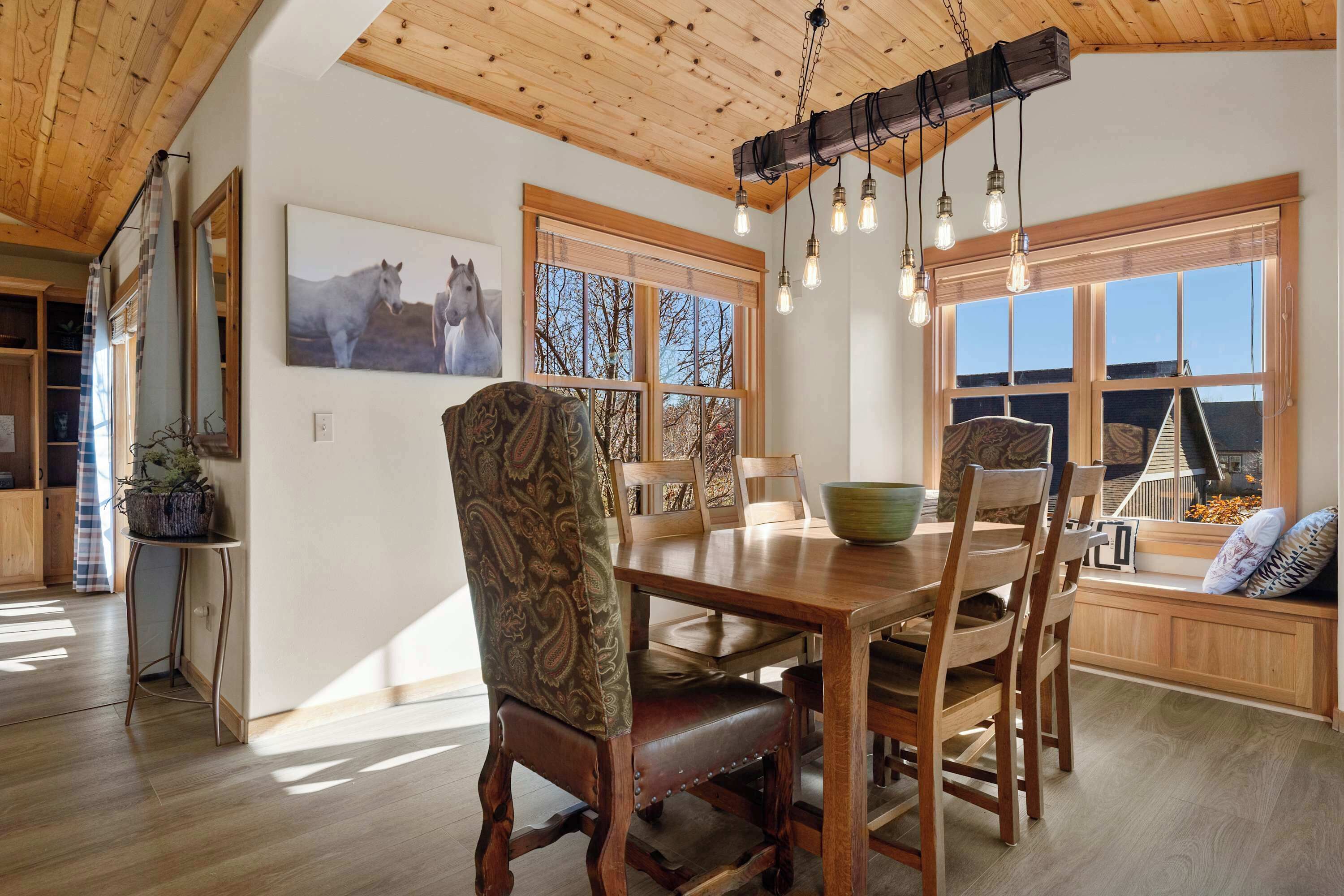 Un comedor con una mesa de madera, sillas y una lámpara colgante.