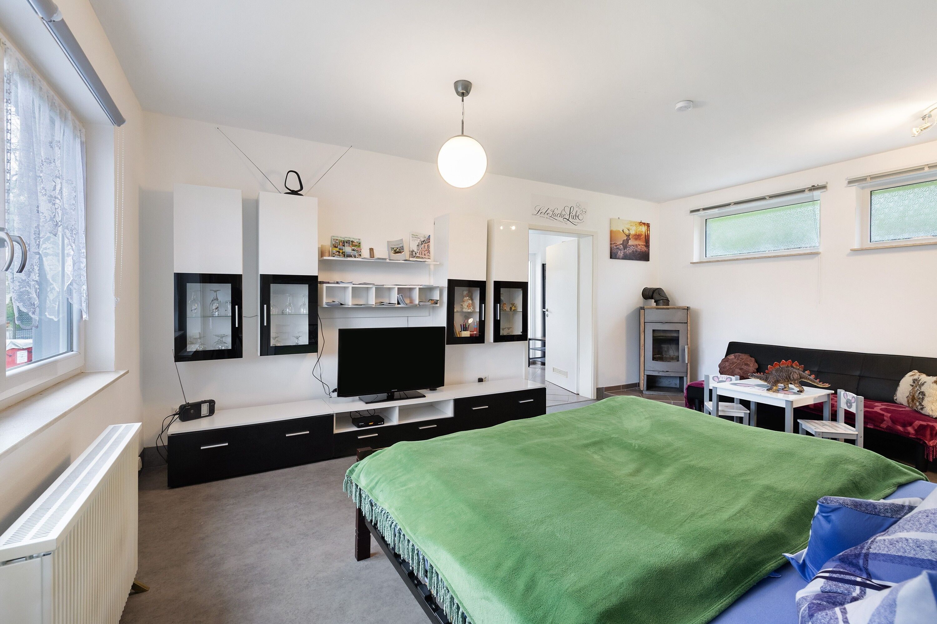 Ein Schlafzimmer mit Bett, Fernseher, Kommode, Schreibtisch und Fenster.