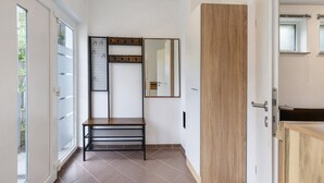 A hallway with a bench, a wooden door, a mirror, and a window.