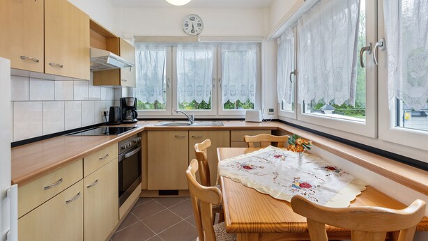 A kitchen with wooden cabinets, a sink, a stove, and a dining table with chairs.