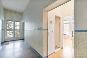 Ein Flur mit einer Tür zu einem Schlafzimmer, das ein Bett und ein Fenster hat.