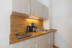 A kitchen with wooden cabinets, a stainless steel sink, and a coffee maker. - Apartment 'Am Schloss Charlottenburg' with Balcony and Wi-Fi (Berlin)