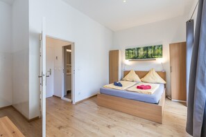 A modern bedroom with a wooden bed, a painting above the bed, and a view of a forest through the window. - Apartment 'Am Schloss Charlottenburg' with Balcony and Wi-Fi (Berlin)