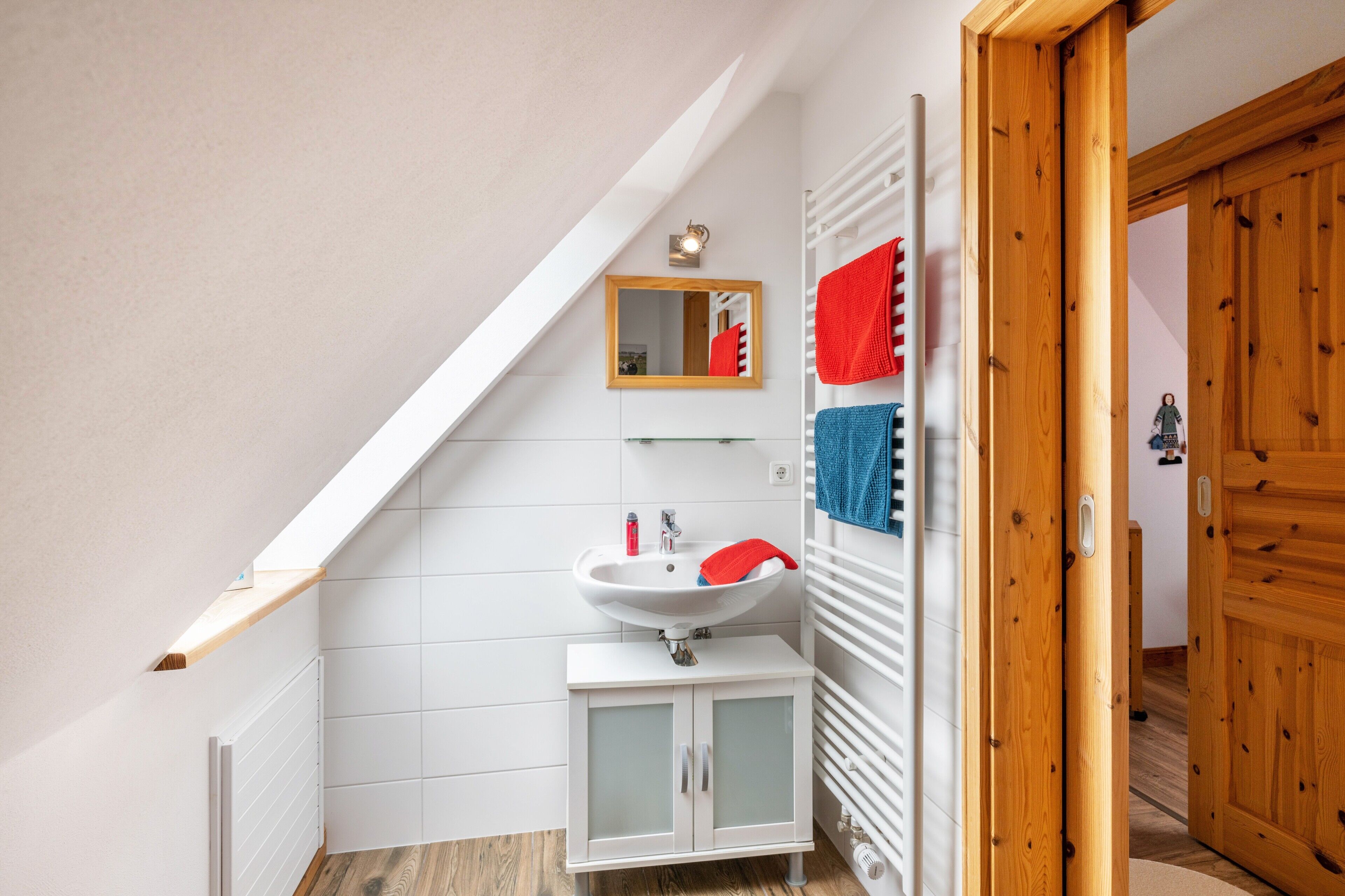 Un baño con un lavamanos blanco, un espejo y puertas de madera.