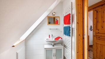 Un baño con un lavamanos blanco, un espejo y puertas de madera.