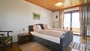 Une chambre à coucher avec un grand lit, une chaise, une table de chevet et un tableau accroché au mur.