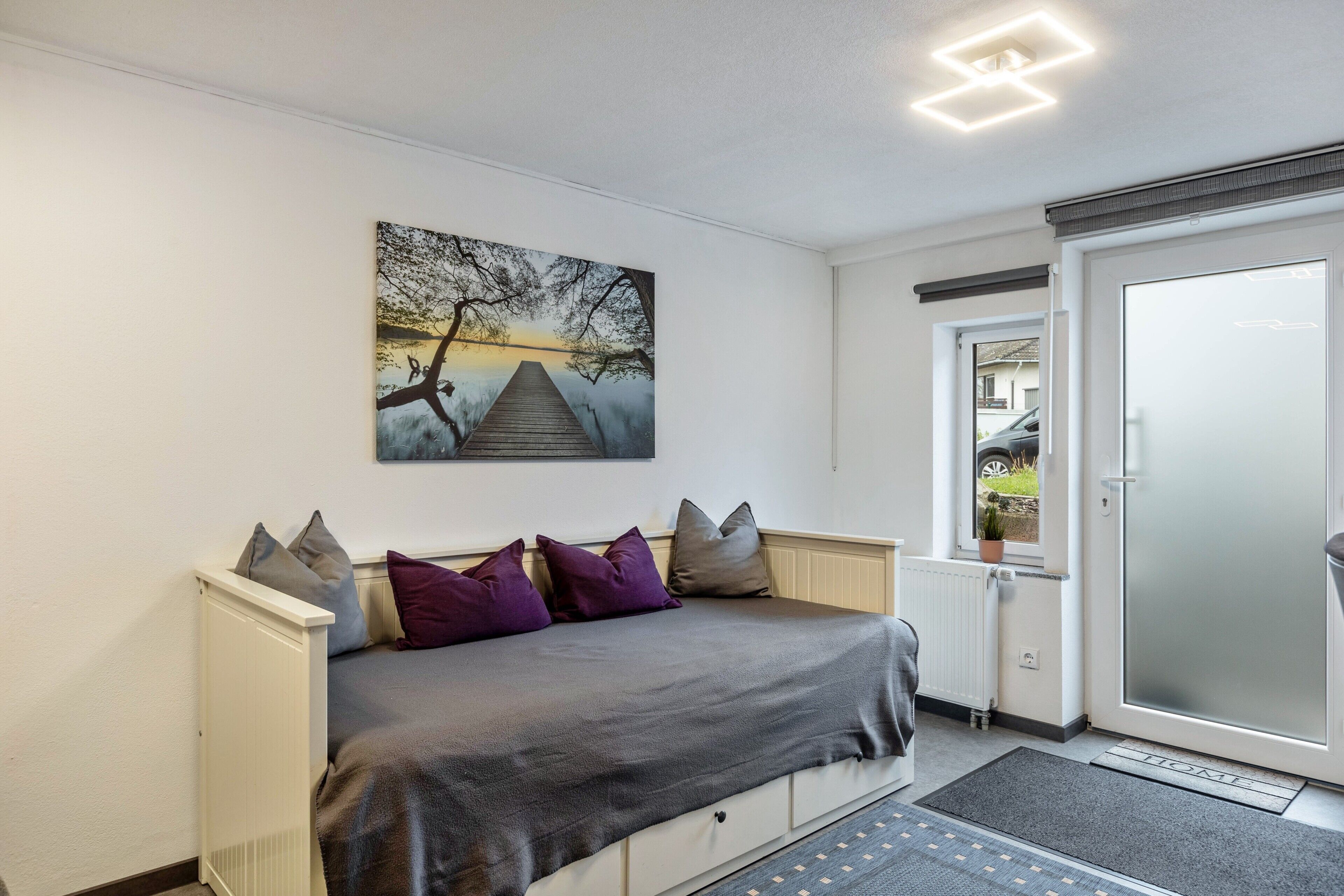 A bedroom with a bed, a radiator, a door, and a window.