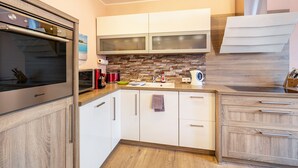 Een moderne keuken met een ingebouwde oven, witte kasten, een mozaïek achterwand en een houten aanrecht.