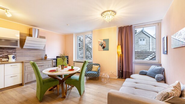 Een moderne leefruimte met een eethoek, keuken en een gezellige zithoek met een bank en een fauteuil.
