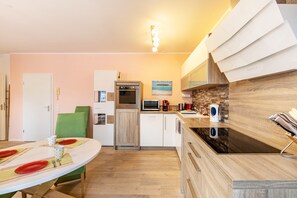 A modern kitchen with a dining table set for two, a microwave, oven, and a coffee maker. - Apartment 'Nr 7' with Wi-Fi (Schwelm)