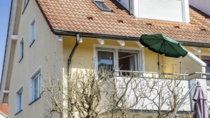 A building with a tiled roof, a balcony with a green umbrella, and a window with a view of the sky. - Apartment 'Haus Grete' with Lake View and Balcony (Langenargen)