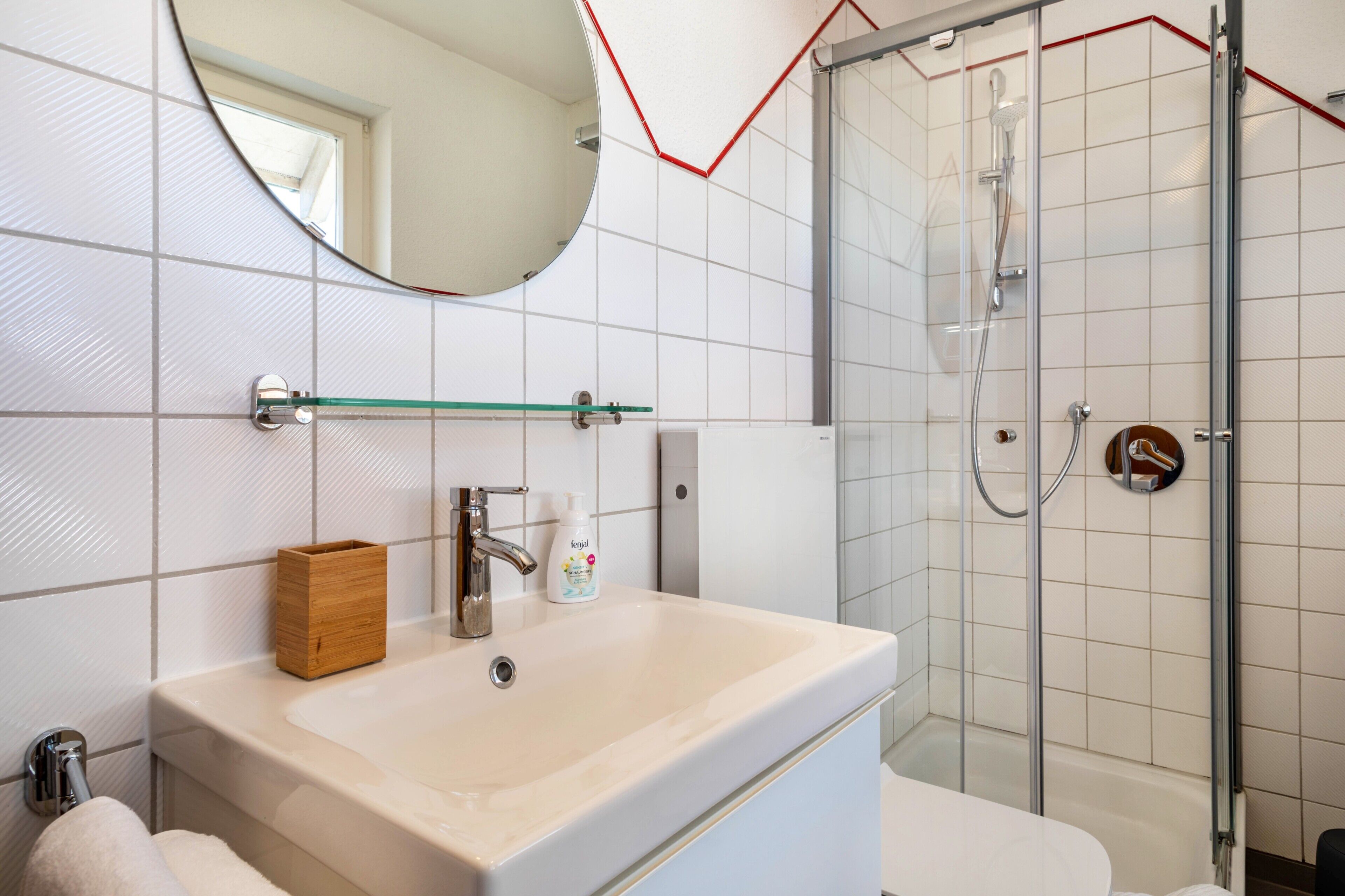 Un bagno con lavandino, specchio, doccia e water.