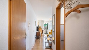 A hallway with a wooden door, a coat rack, a mirror, a small table with a lamp, and a chair. - Apartment 'Haus Grete' with Lake View and Balcony (Langenargen)