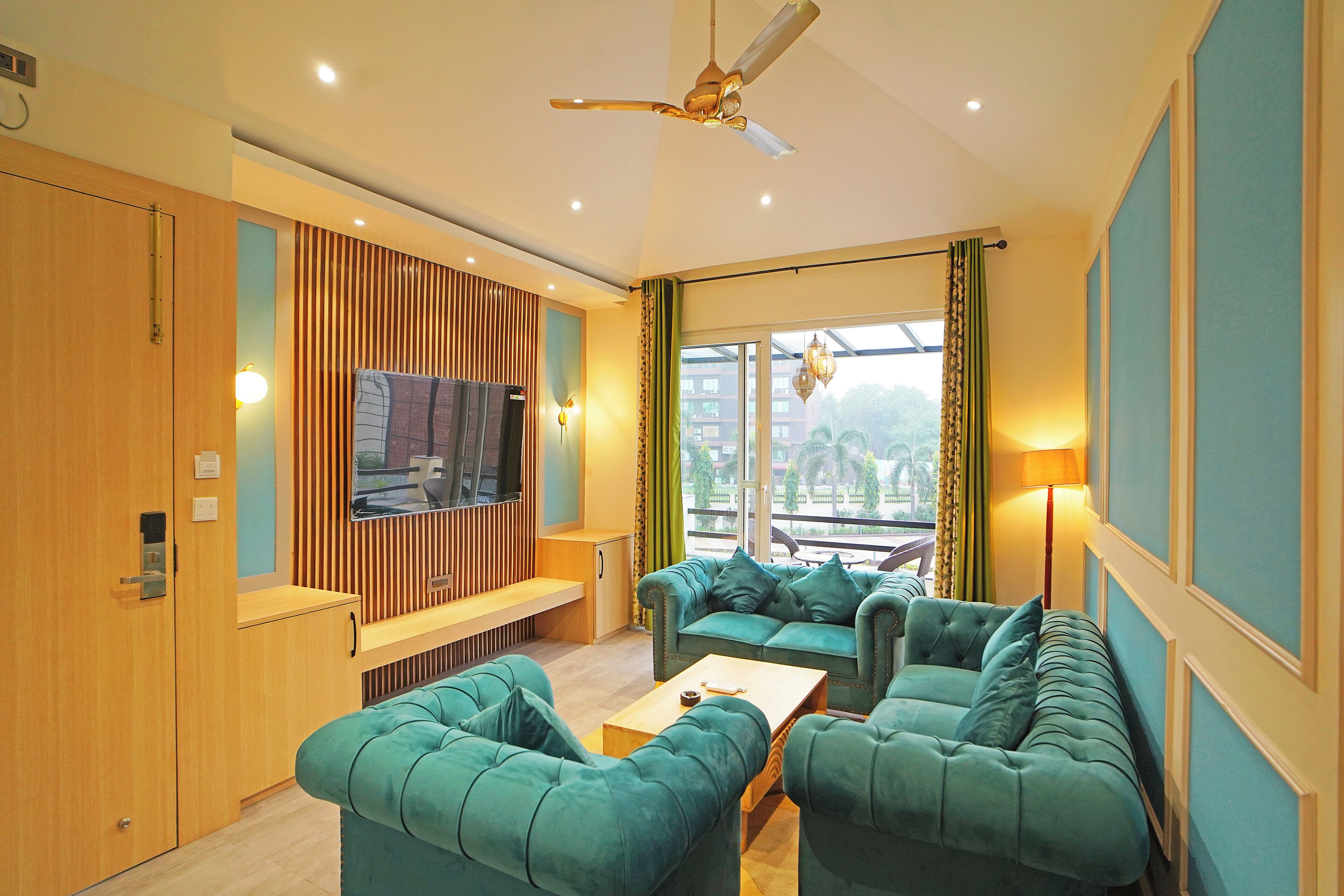 A modern living room with a sofa set, a television, and a ceiling fan.
