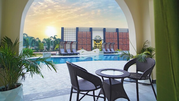 Zona junto a la piscina con vista a un edificio, sillas de descanso y una mesa.