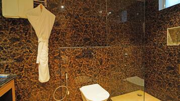 Un baño con cabina de ducha de vidrio, una bañera blanca y una bata colgada en un perchero.