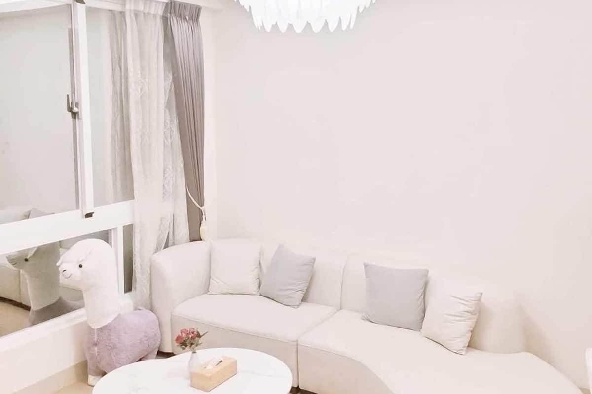 A modern living room with a white sofa, a round coffee table, and a chandelier.