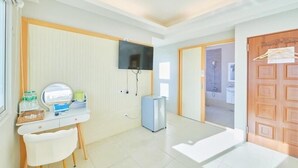 Ein sauberes, modernes Zimmer mit Schreibtisch, Stuhl und einem an der Wand befestigten Fernseher.