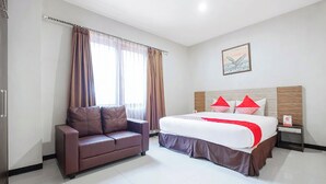 A hotel room with a bed, a sofa, and a painting on the wall. - Hotel O Marina Andalas (Makassar)