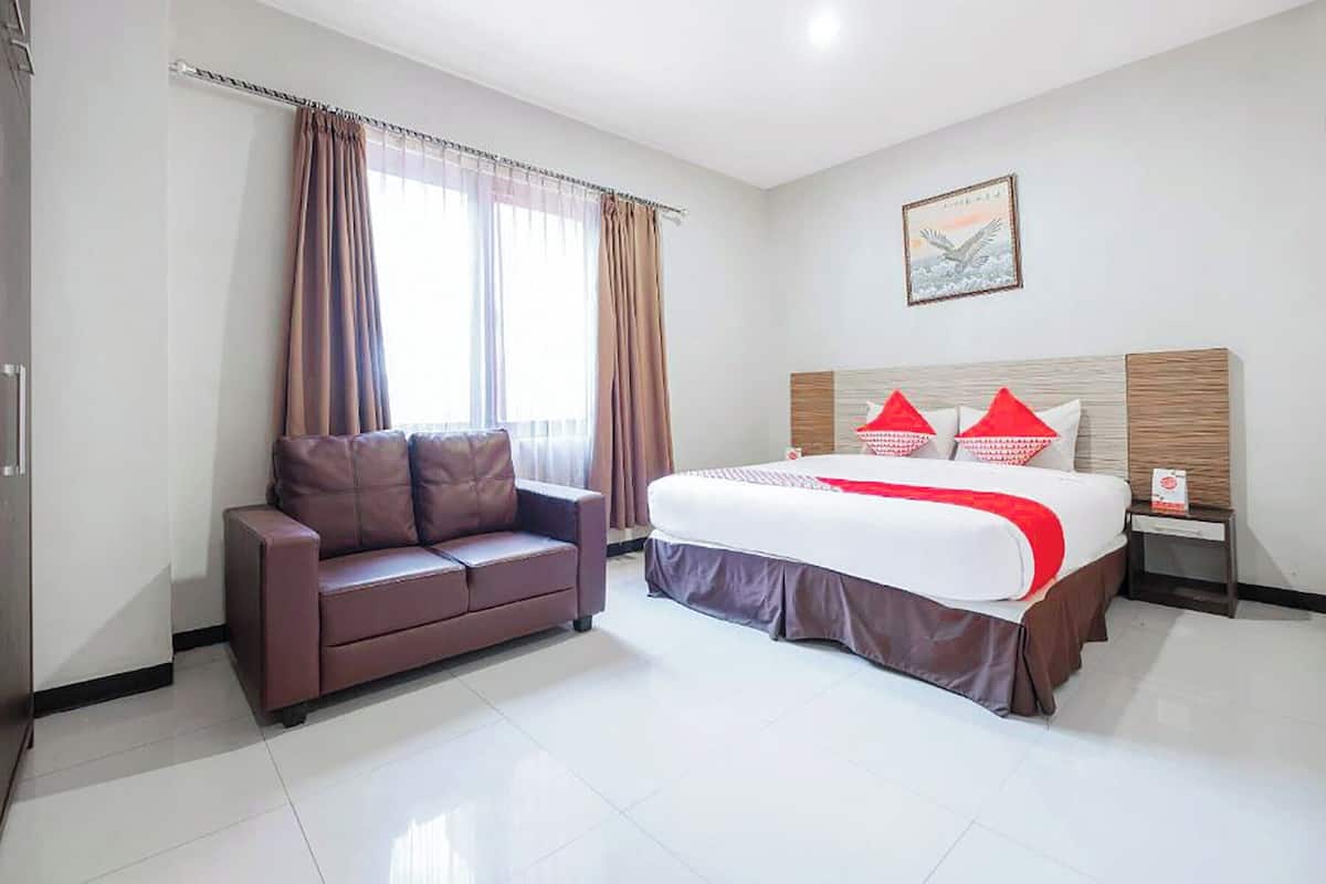 A hotel room with a bed, a sofa, and a painting on the wall.