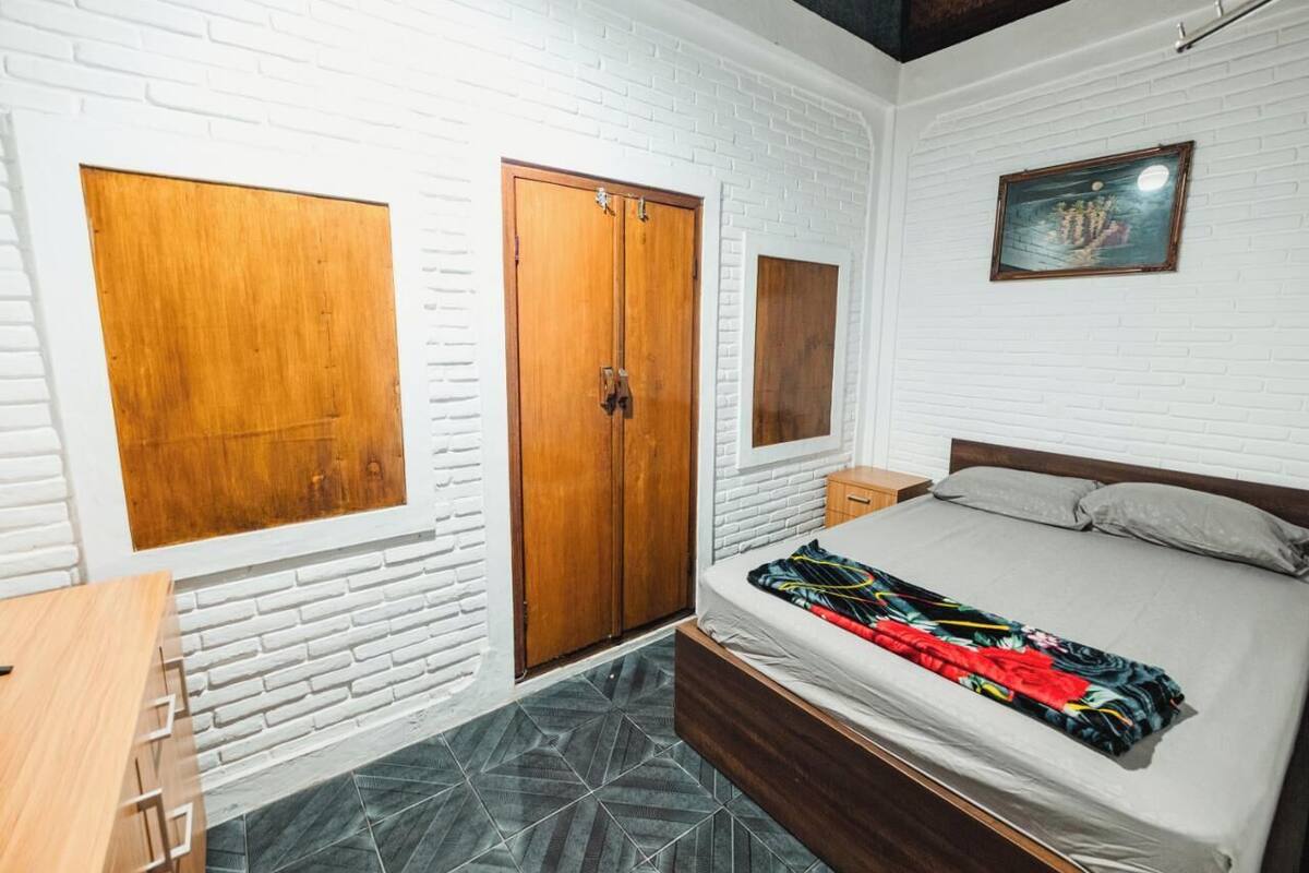 A bedroom with a bed, a wardrobe, a desk, and a small table.