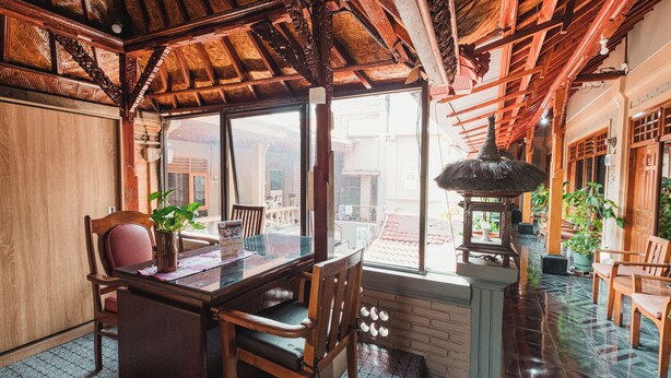 A traditional wooden interior with a dining area, large windows, and a tiled floor. - Tempo Doeloe Homestay (Kuta)