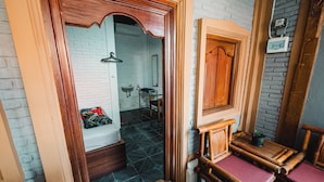 A bathroom with a white brick wall, a wooden door, a mirror, and a sink. - Tempo Doeloe Homestay (Kuta)