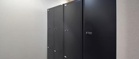 A row of black metal lockers with a simple, utilitarian design against a plain wall.