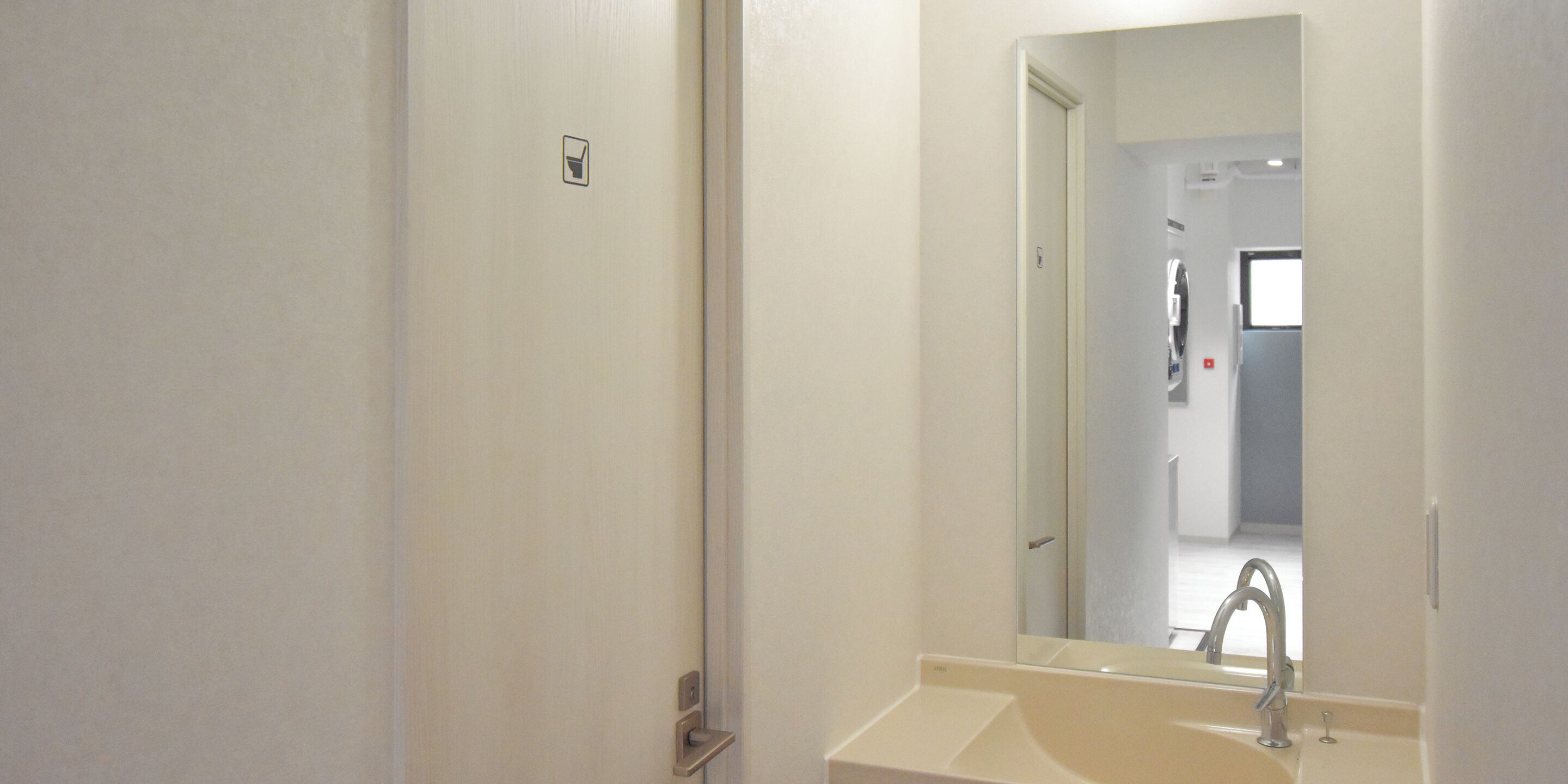 A bathroom with a sink, mirror, and door.