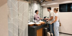 A reception area with a counter, a staff member, and guests. - HOTEL WINDS ASAKUSA Capsule Inn - Hostel (Tokyo)