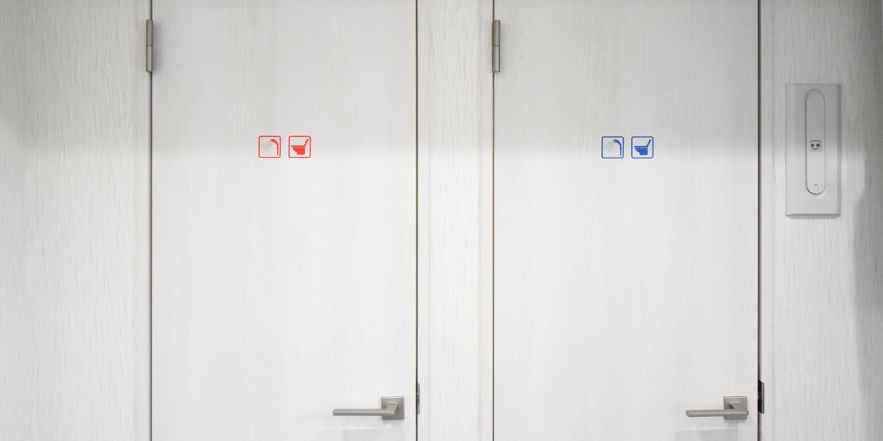 A set of white doors with red and blue restroom symbols indicating facilities.