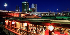Un restaurante con decoración tradicional, vistas del horizonte de la ciudad y un puente al fondo.