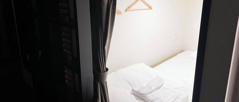Una habitación de hotel con una cama, un perchero de madera y una cortina.