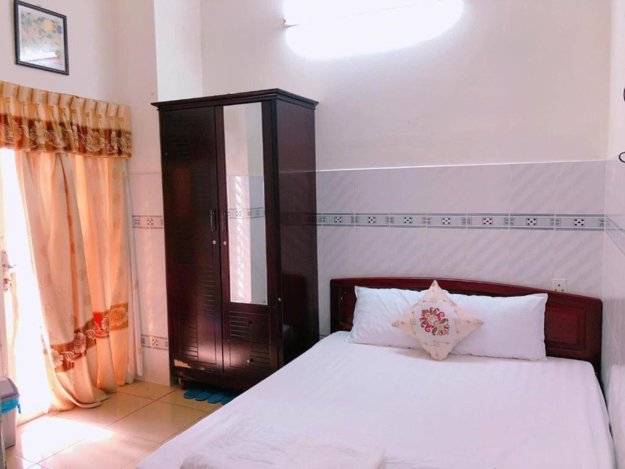 A bedroom with a bed, a wardrobe, and a window with curtains.