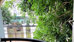 Een balkon met smeedijzeren hekwerk, met uitzicht op een straat met gebouwen en groen.