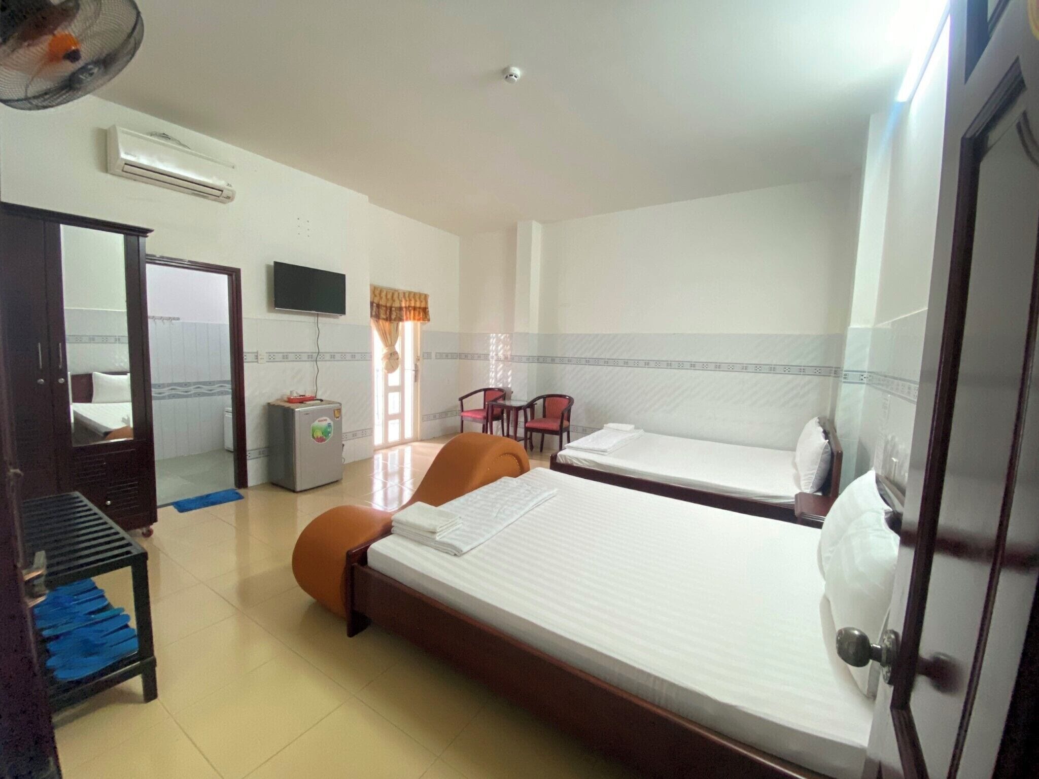 Habitación de hotel con dos camas, un escritorio, una silla, un televisor y un equipo de aire acondicionado.