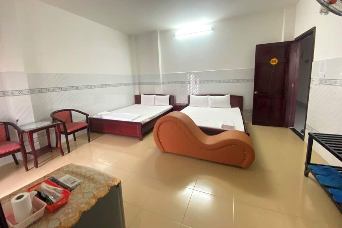 Habitación de hotel con dos camas, un escritorio, una silla, una mesita con artículos de aseo y un armario.