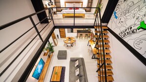 Un intérieur moderne avec une chambre à coucher aménagée dans le style d’un loft, un coin repas et un escalier.
