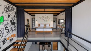 Une chambre moderne avec un grand lit, une carte accrochée au mur et un escalier menant à un niveau supérieur.